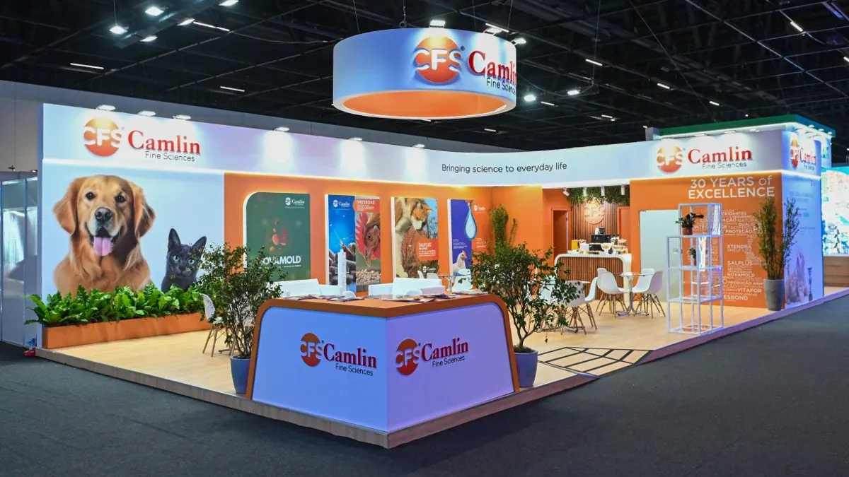 Estande da CAMLIN na FENAGRA 2026, com luminoso circular suspenso, balcão de recepção e painéis da marca.